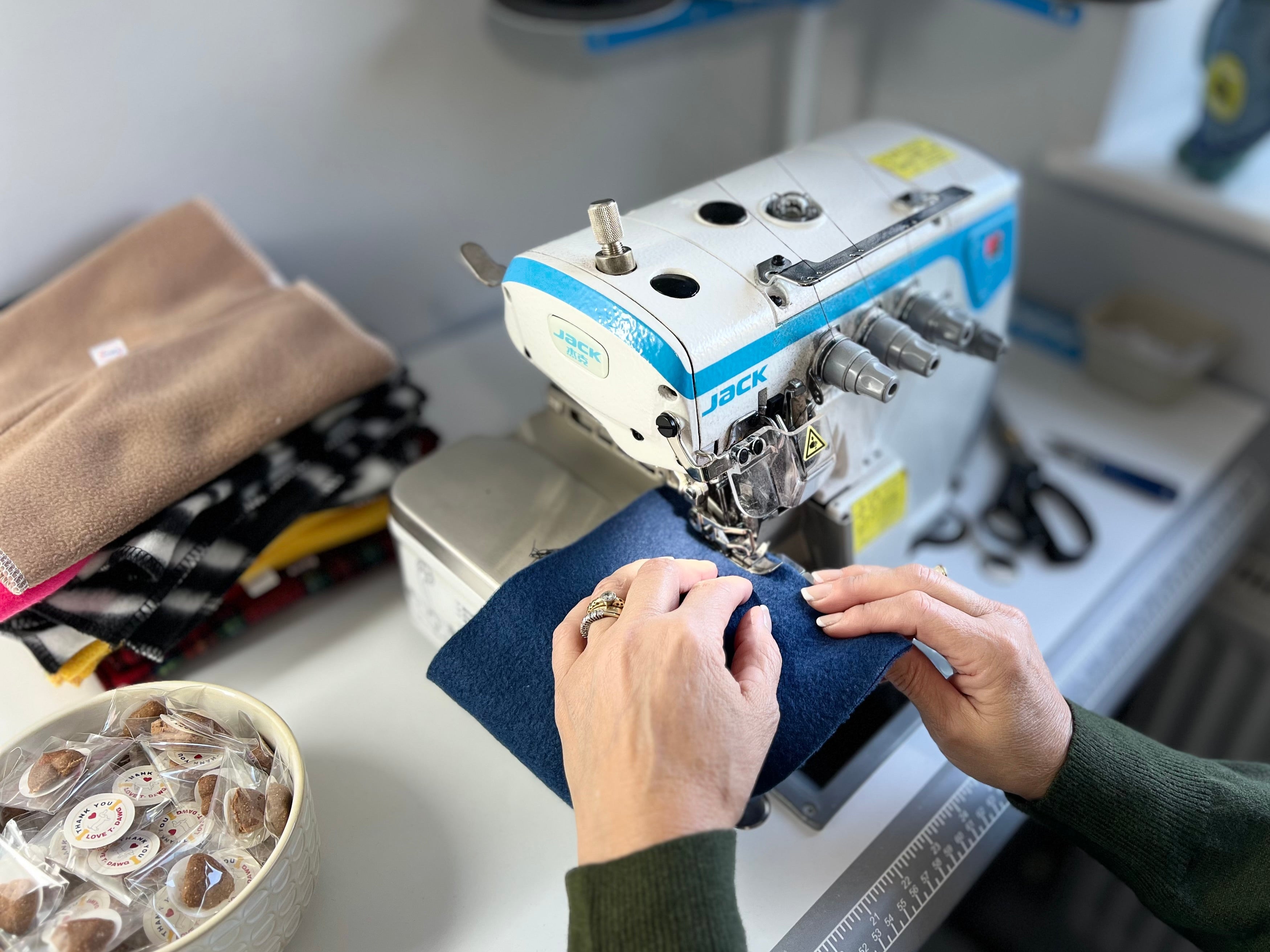 Person using a sewing machine on a table with various items in the background